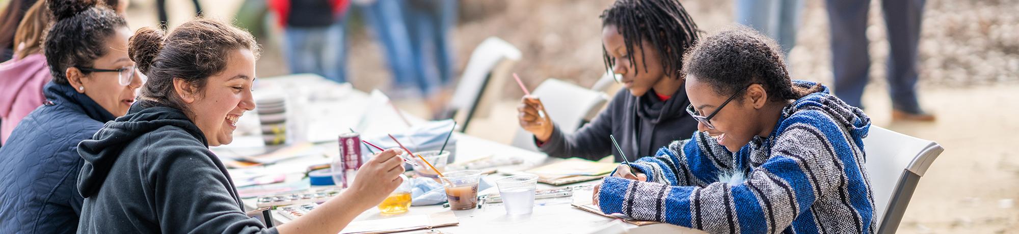 Participants painting at a table at a Biodiversity Museum Day exhibit.